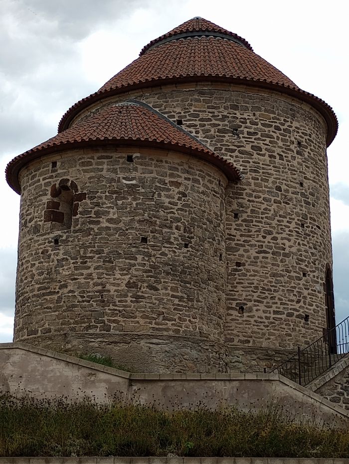 A Romanesque stone tower with a distinct round shape and tiled roof, showcasing historical architecture.